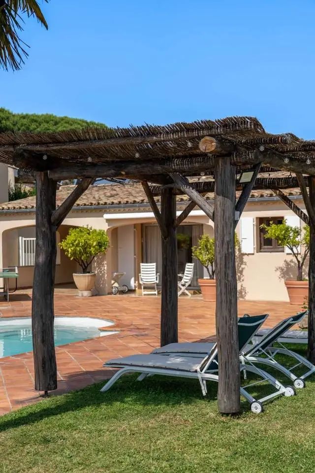 Pergola en bois et transats au bord de la piscine