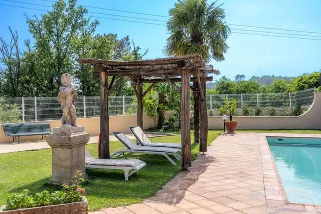 Pergola, transats et statue au bord de la piscine