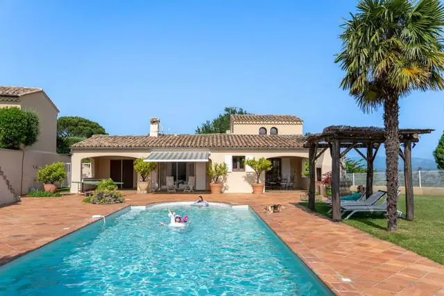 Vue large de la villa et de la piscine depuis le jardin